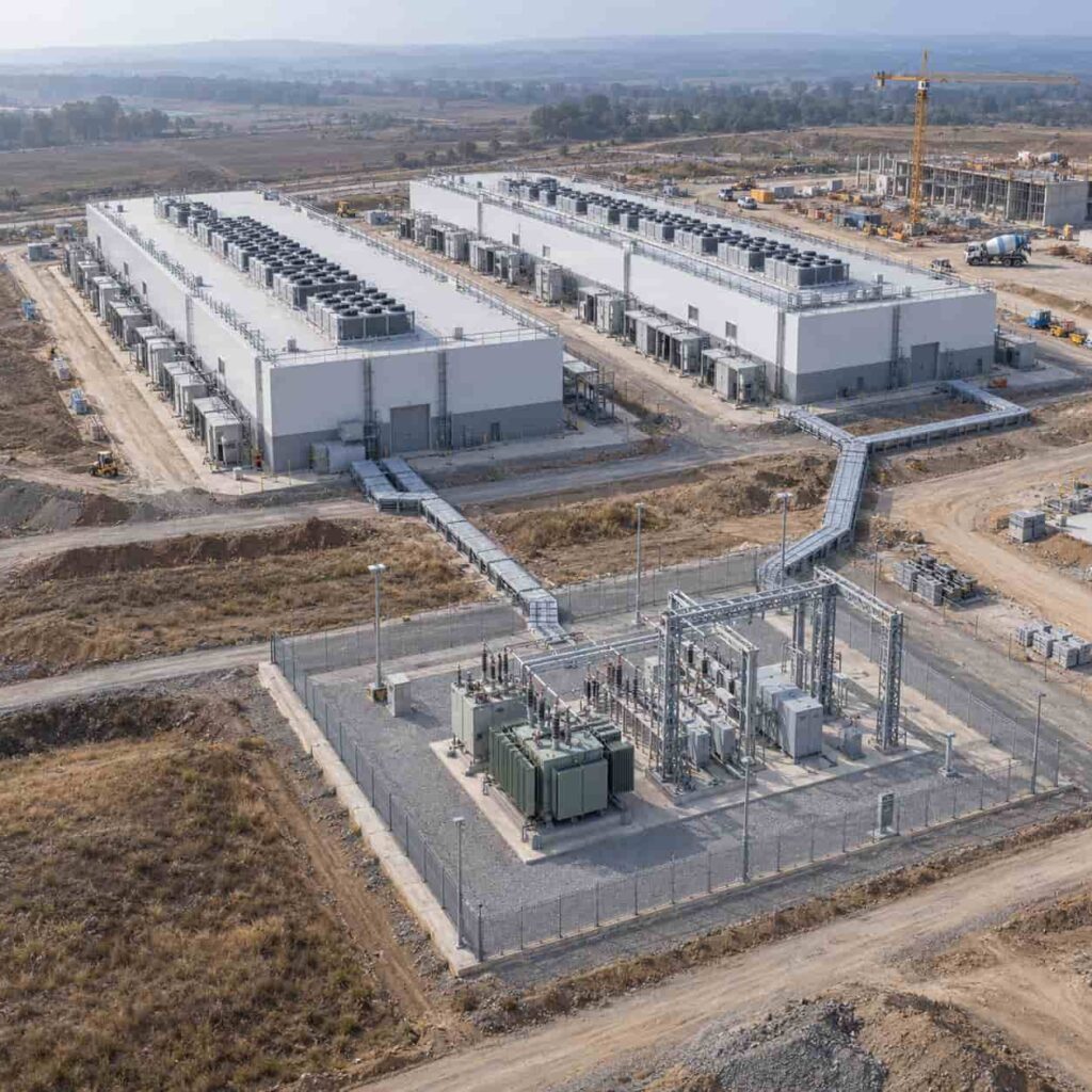 Aerial view of a large data center campus under construction with substations and power feeders